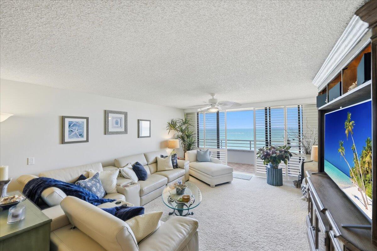 A living room with white leather sofas, a glass coffee table, and a balcony view — 9950 S Ocean Drive # 604, Jensen Beach FL 34957, JENSEN BEACH, FL