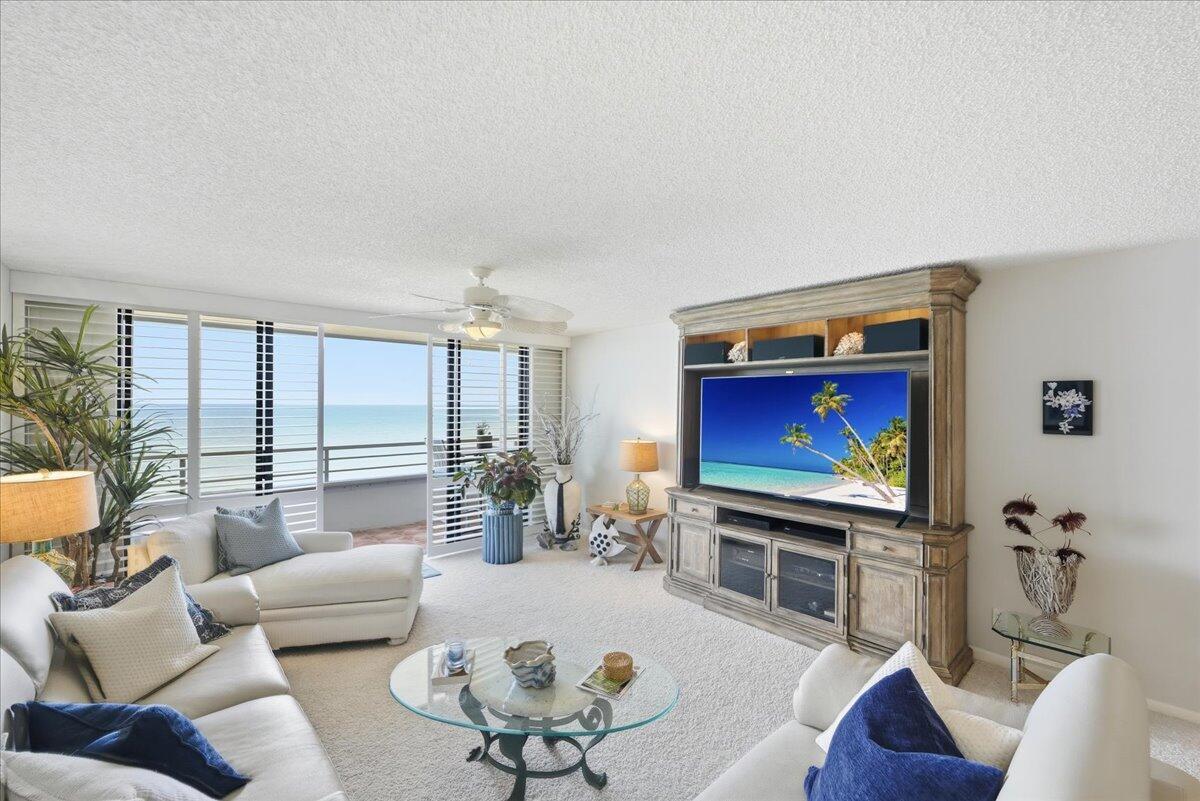 A living room with white sofas, a glass coffee table, and a large ocean-view balcony — 9950 S Ocean Drive # 604, Jensen Beach FL 34957, JENSEN BEACH, FL