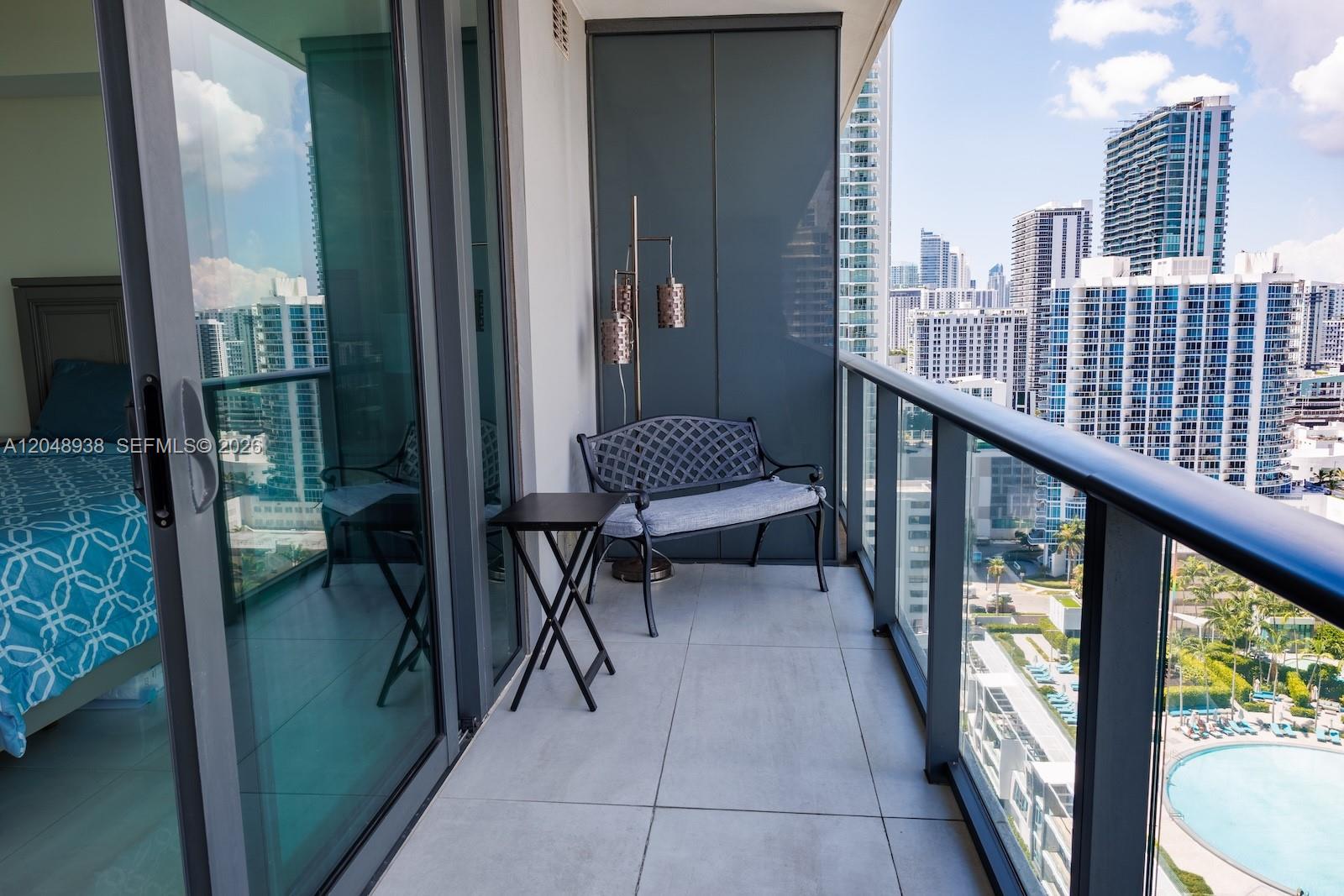 A balcony features a metal bench, a small side table, and a floor lamp — 3131 NE 7th Ave # 2003, Miami FL 33137, MIAMI, FL