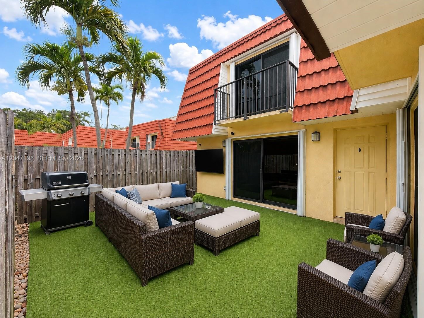 A fenced patio features artificial turf, outdoor wicker furniture, a grill, and a yellow door — 9955 NW 6th Ct, Plantation FL 33324, PLANTATION, FL