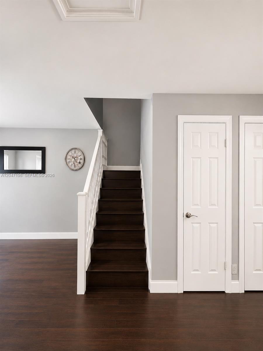 A staircase with dark wood treads and a white railing stands beside two white doors — 9955 NW 6th Ct, Plantation FL 33324, PLANTATION, FL