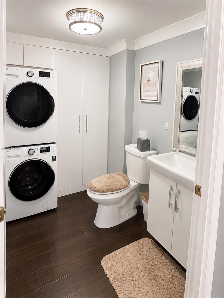 A laundry room and bathroom combination featuring a stacked washer-dryer, toilet, and vanity — 9955 NW 6th Ct, Plantation FL 33324, PLANTATION, FL