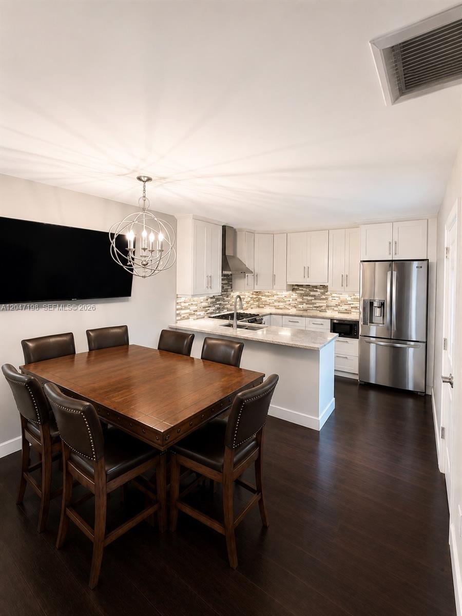 A dining area with a wooden table and chairs sits adjacent to a modern kitchen — 9955 NW 6th Ct, Plantation FL 33324, PLANTATION, FL