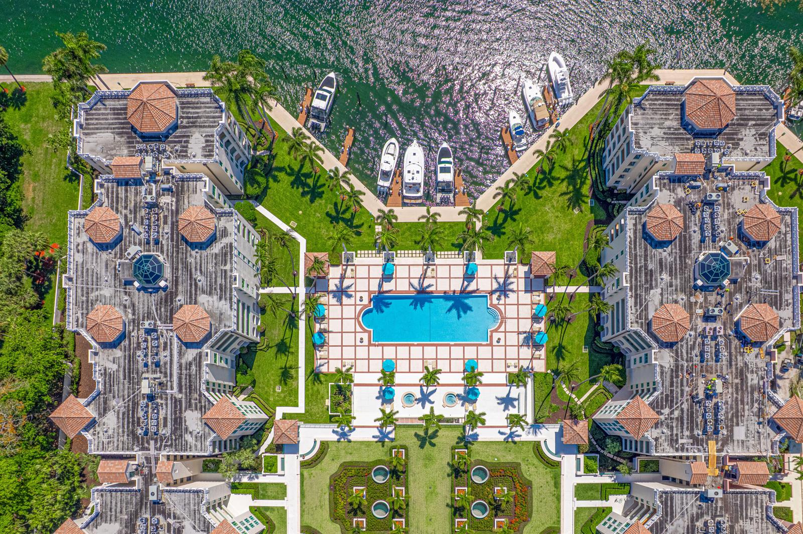 An aerial view shows two large buildings flanking a central swimming pool and boat docks — 100 SE 5th Avenue # 412, Boca Raton FL 33432, BOCA RATON, FL
