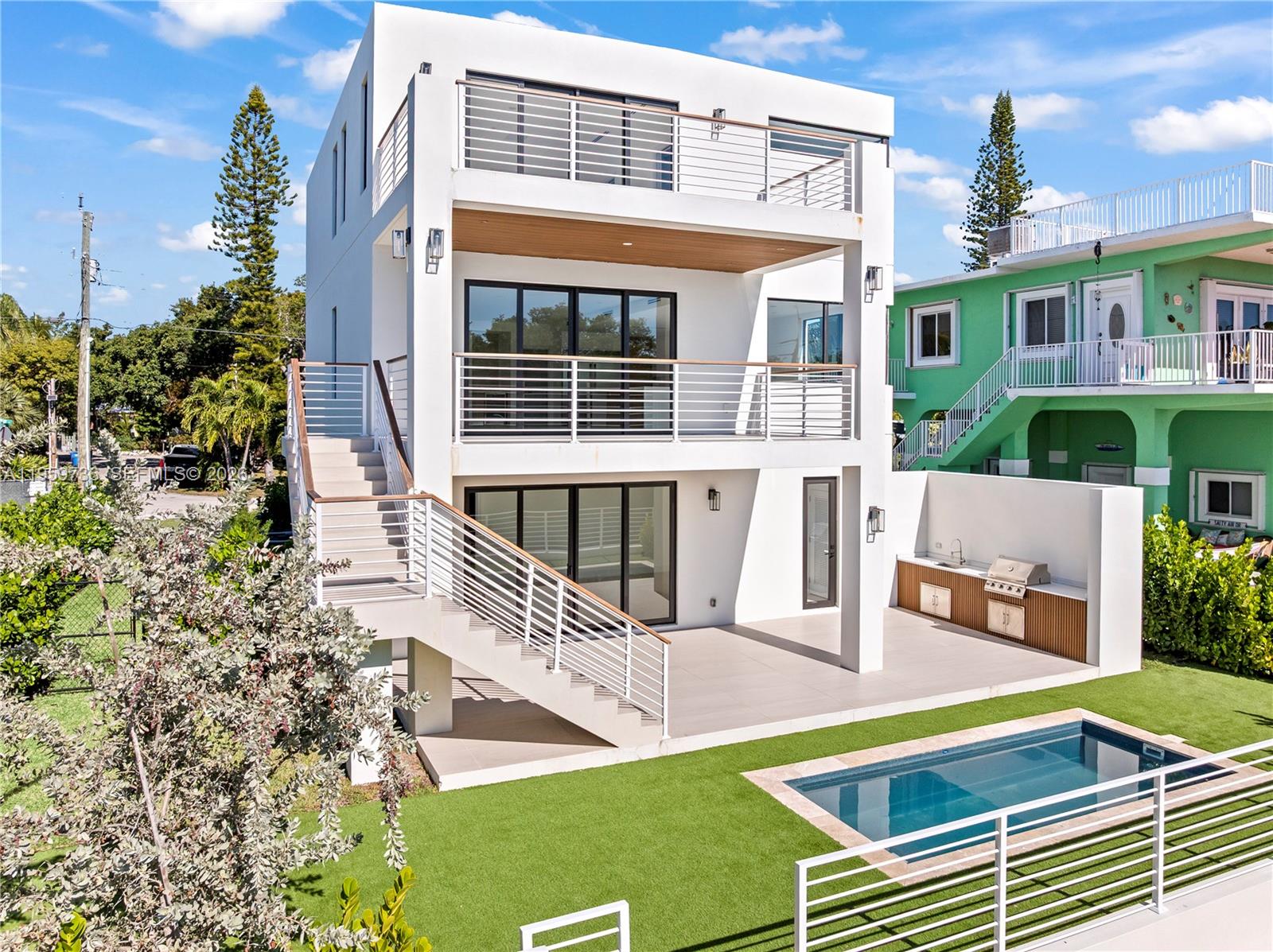 A modern three-story white house features exterior stairs, balconies, a patio, and a swimming pool — 124 Orchid St, Plantation Key FL 33070, PLANTATION KEY, FL