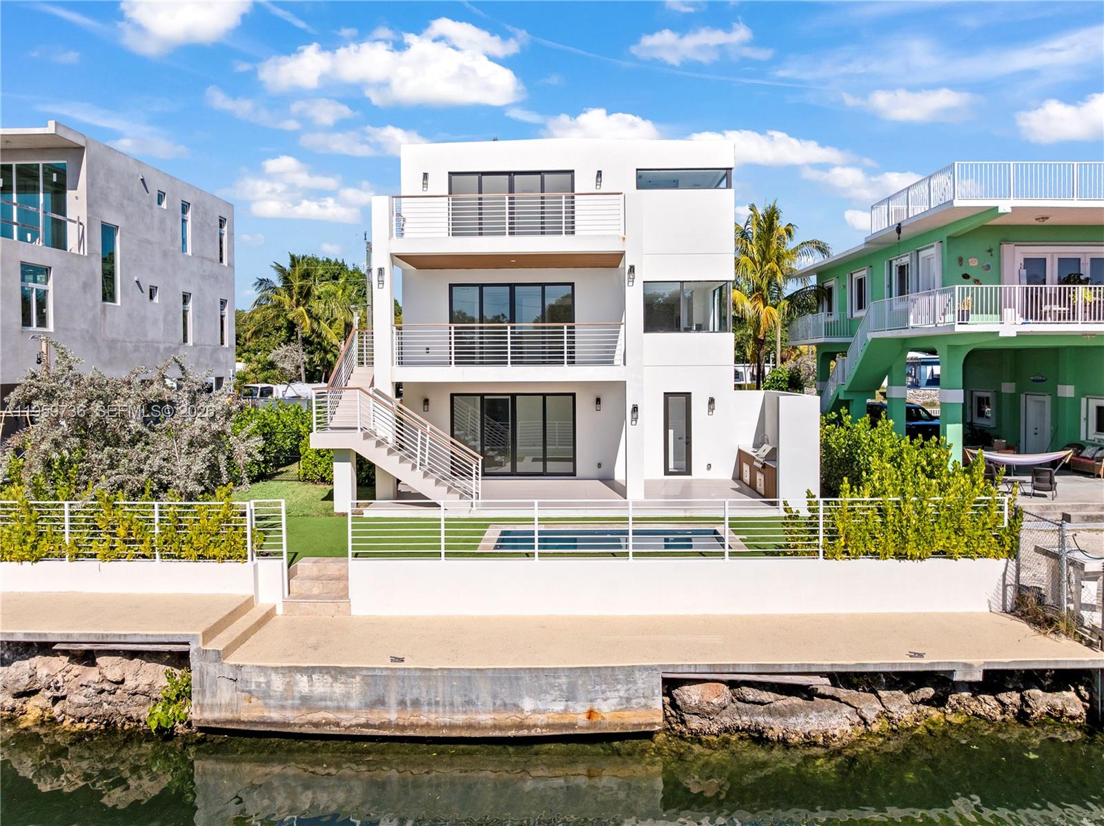 A modern three-story white house features balconies, an outdoor staircase, and a waterfront swimming pool — 124 Orchid St, Plantation Key FL 33070, PLANTATION KEY, FL