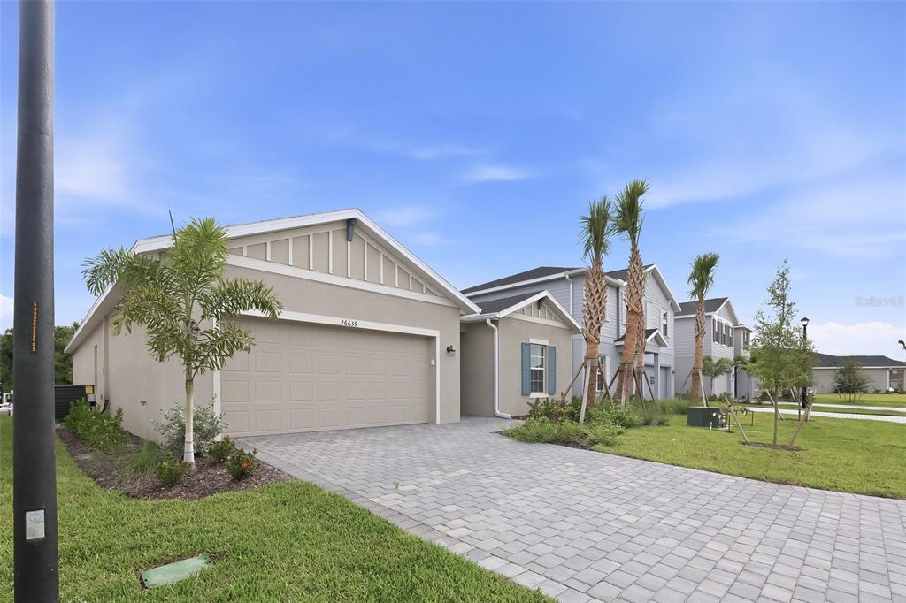 A single-story house with a beige stucco exterior, a two-car garage, and a paved driveway — 26639 WILGROVE PLACE, PUNTA GORDA, FL