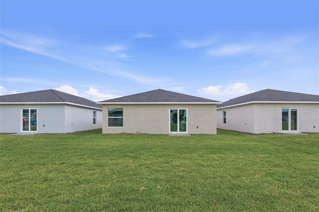 The rear exterior view shows three single-story houses with lawns under a blue sky — 26639 WILGROVE PLACE, PUNTA GORDA, FL