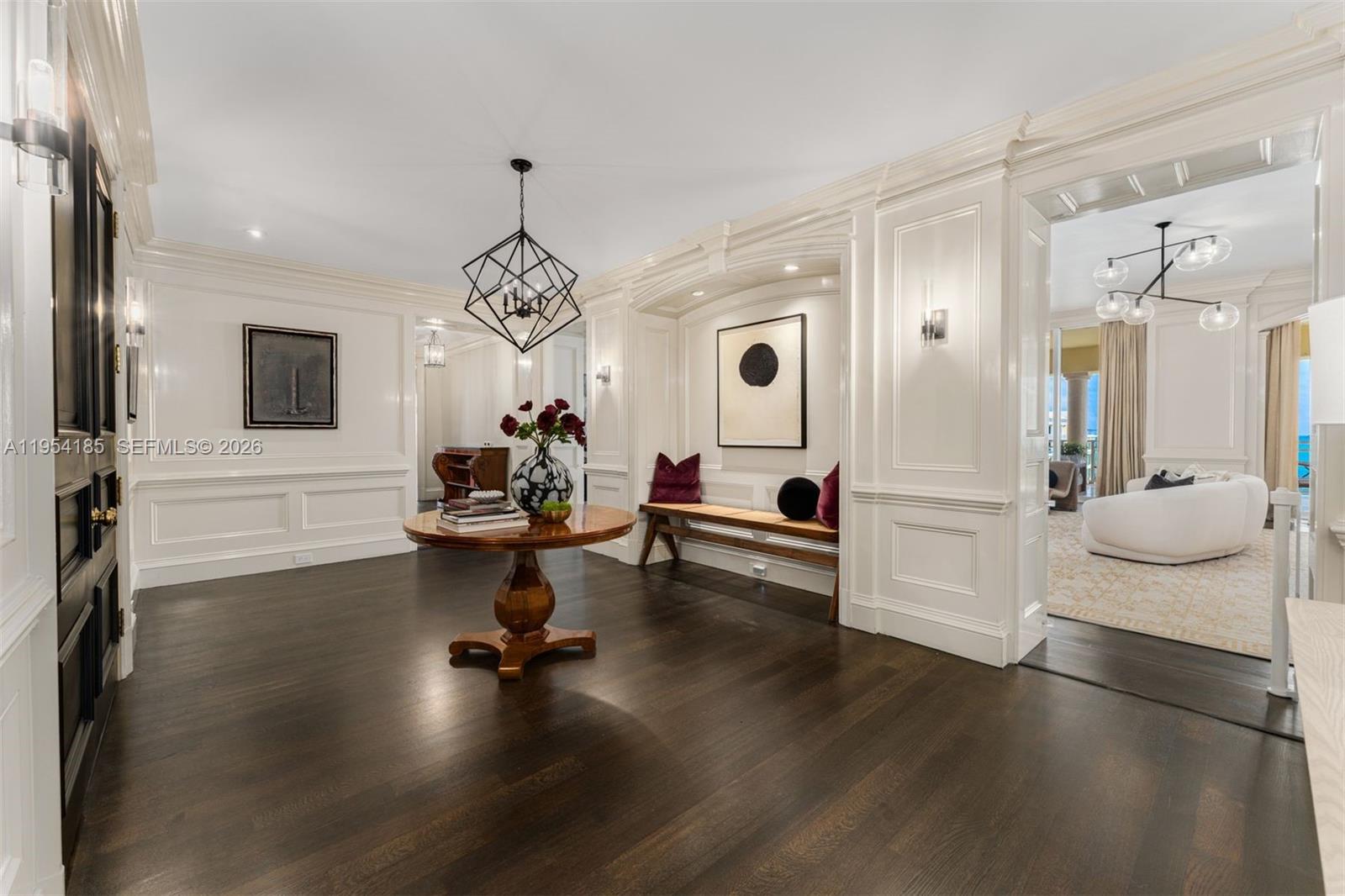 A foyer features dark hardwood floors, white wainscoting, a round wooden table, and a built-in bench — 445 Grand Bay Drive # 1A, Key Biscayne FL 33149, KEY BISCAYNE, FL