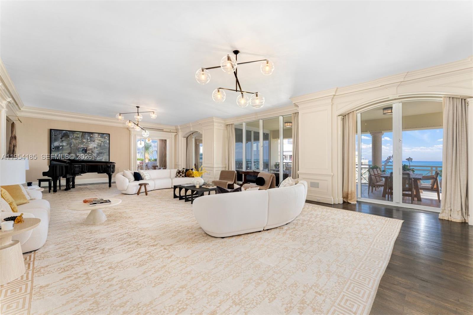 A spacious living room features white curved sofas, a grand piano, and ocean-view balcony access — 445 Grand Bay Drive # 1A, Key Biscayne FL 33149, KEY BISCAYNE, FL