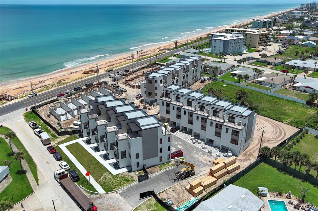 An aerial view shows a coastal construction site with modern townhomes near the ocean — 2360 OCEAN SHORE BOULEVARD UNIT 20, ORMOND BEACH, FL