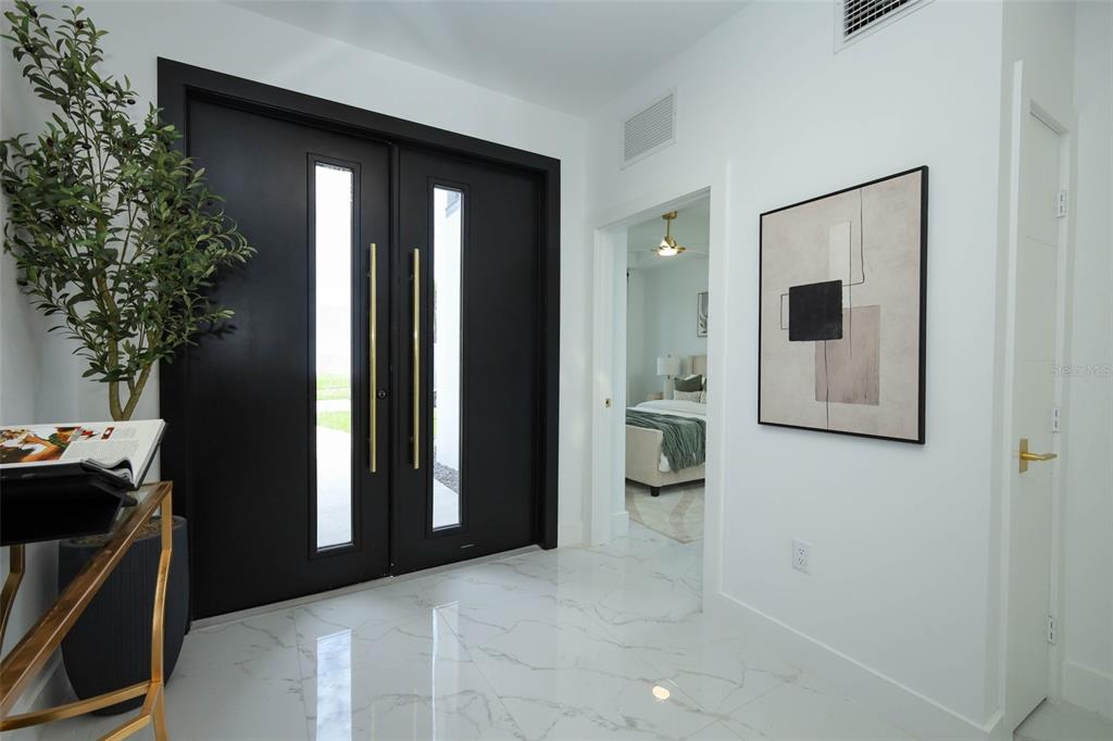 A bright entryway features black double doors, white marble flooring, and a framed abstract painting — 2360 OCEAN SHORE BOULEVARD UNIT 20, ORMOND BEACH, FL