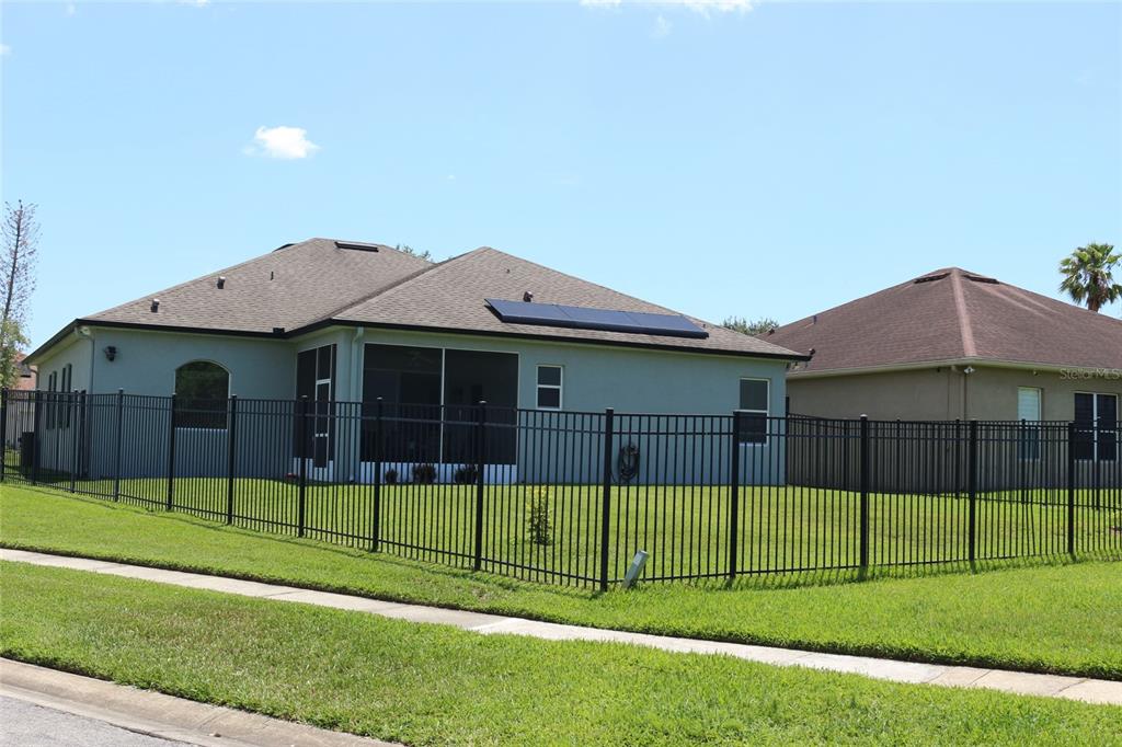 The exterior rear view of a house features a screened-in patio and solar panels — 2500 CORBYTON COURT, ORLANDO, FL