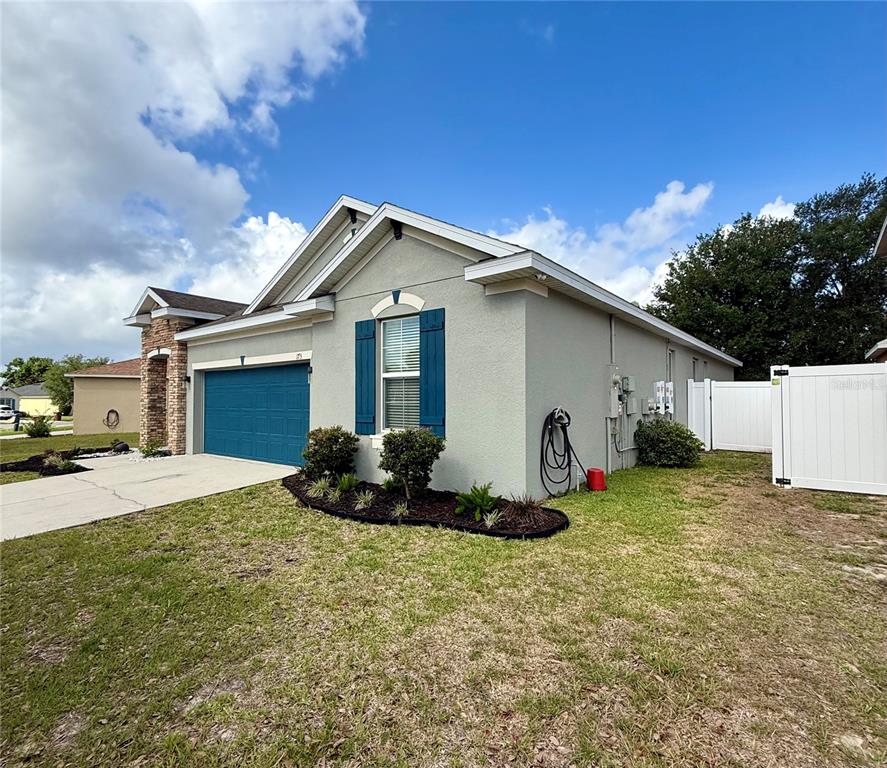 A single-story house with a blue garage door, blue shutters, and a white vinyl fence — 173 TRACY CIRCLE, HAINES CITY, FL