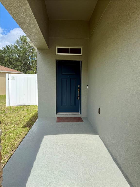 A covered concrete entryway leads to a dark blue front door with a transom window — 173 TRACY CIRCLE, HAINES CITY, FL