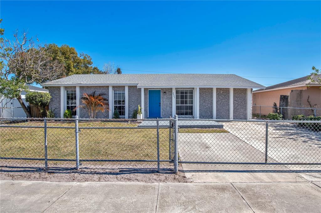 A single-story house with a gray stone facade, a blue front door, and a chain-link fence — 4027 GANDER AVENUE, ORLANDO, FL