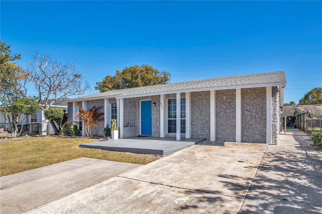 A single-story house with a gray stone facade, a bright blue door, and a driveway — 4027 GANDER AVENUE, ORLANDO, FL