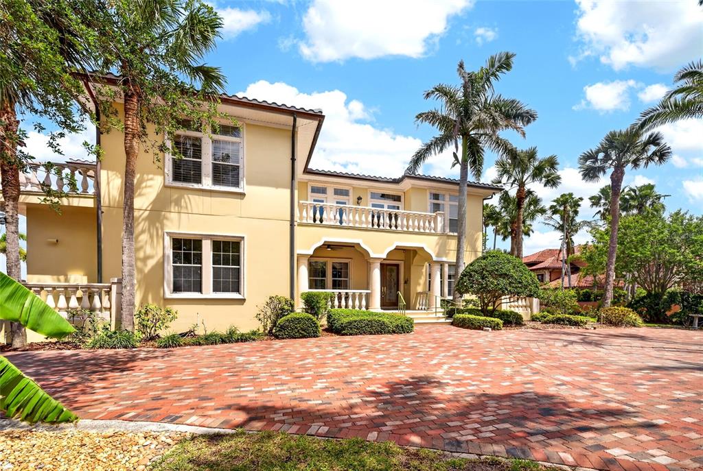 A two-story yellow stucco house features a brick driveway and a second-floor balcony — 115 18TH STREET, BELLEAIR BEACH, FL