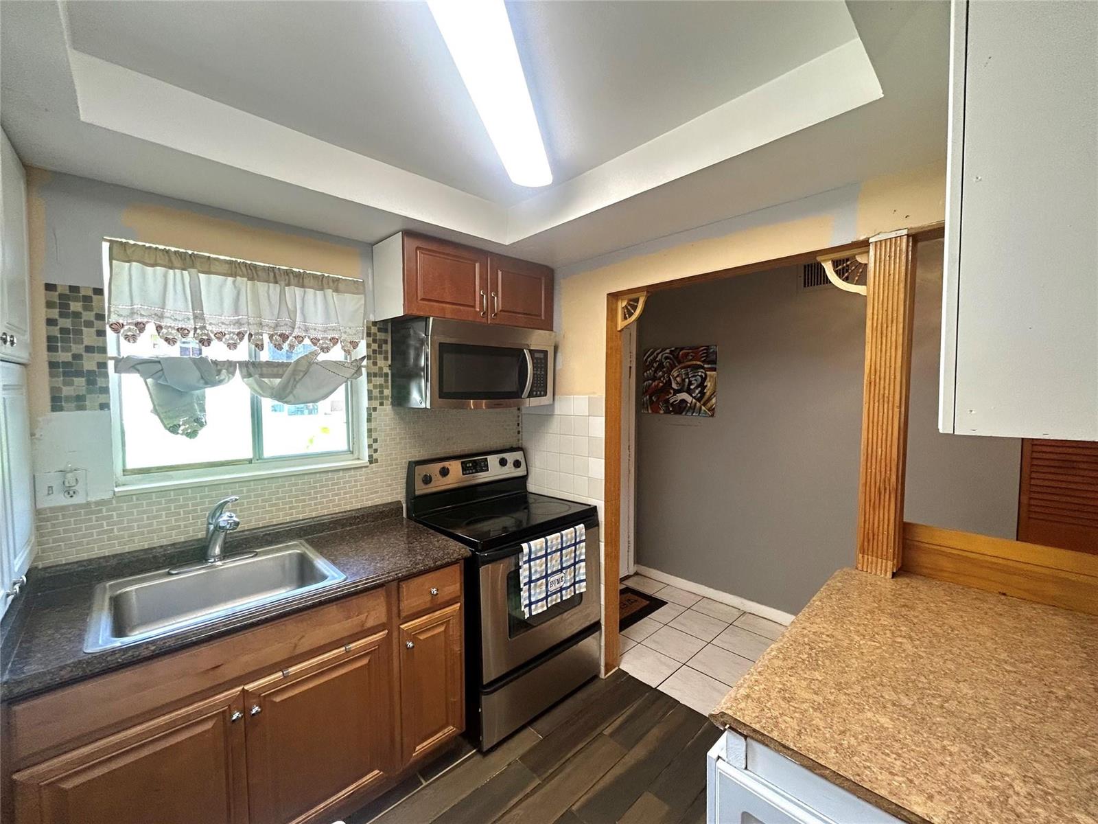 A kitchen features wood cabinets, stainless steel appliances, a sink, and a tiled backsplash — 6100 Forest Hill Boulevard # 101, West Palm Beach FL 33415, WEST PALM BEACH, FL