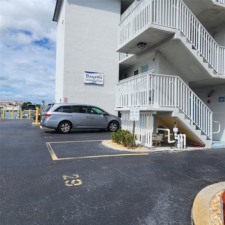 A silver minivan is parked in a lot next to a multi-story building with stairs — 800 BAYWAY BOULEVARD UNIT 28, CLEARWATER BEACH, FL