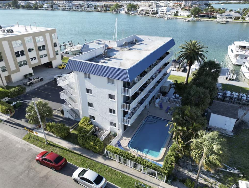 An aerial view shows a multi-story apartment building with a swimming pool and waterfront docks — 800 BAYWAY BOULEVARD UNIT 28, CLEARWATER BEACH, FL