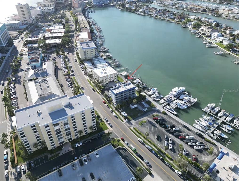 An aerial view shows a coastal area with multi-story buildings, parking lots, and a marina — 800 BAYWAY BOULEVARD UNIT 28, CLEARWATER BEACH, FL