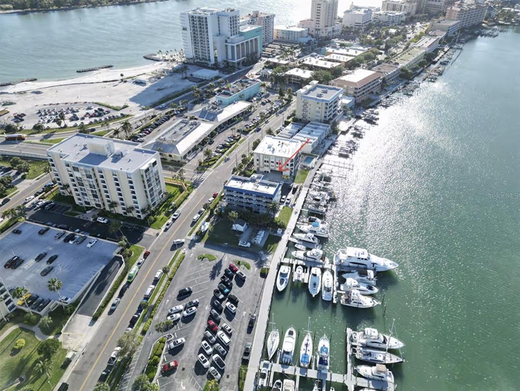 An aerial view shows a waterfront condominium complex with a marina and nearby beach — 800 BAYWAY BOULEVARD UNIT 28, CLEARWATER BEACH, FL