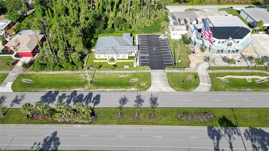An aerial view shows a house, a parking lot, and a commercial building with a flag — 17178 TOLEDO BLADE BOULEVARD, PORT CHARLOTTE, FL