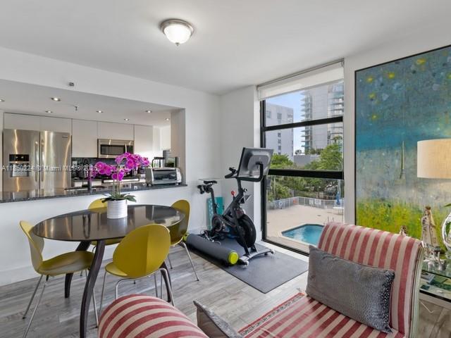 A dining area with a kitchen and exercise bike overlooks a pool through large windows — 2501 Brickell Ave # 307, Miami FL 33129, MIAMI, FL