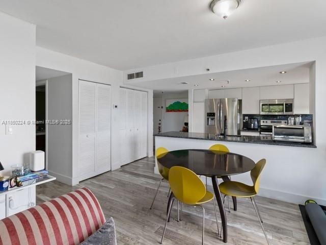 An open-concept kitchen and dining area features a round table with yellow chairs and cabinetry — 2501 Brickell Ave # 307, Miami FL 33129, MIAMI, FL