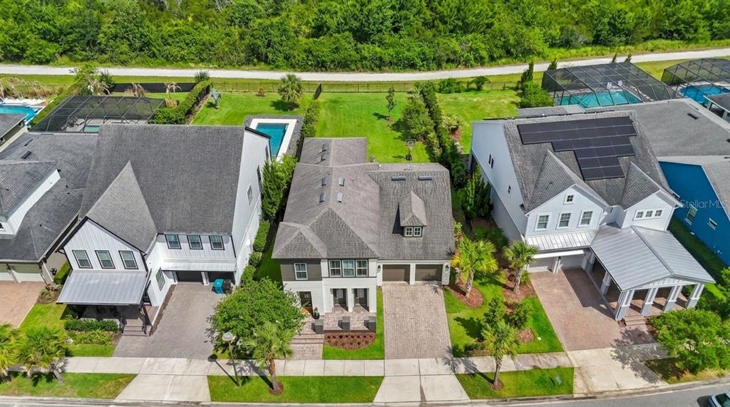 An aerial view shows three suburban houses with driveways, pools, and green backyards — 9542 REYMONT STREET, ORLANDO, FL
