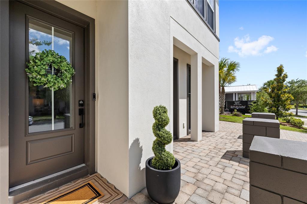 A front entryway features a dark door with a wreath, a spiral topiary, and pavers — 9542 REYMONT STREET, ORLANDO, FL