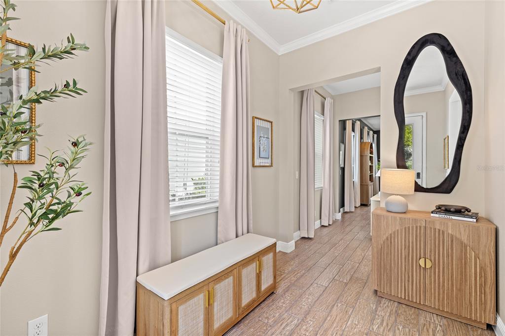 A bright entryway features a wooden bench, a matching cabinet, and a large organic-shaped mirror — 9542 REYMONT STREET, ORLANDO, FL