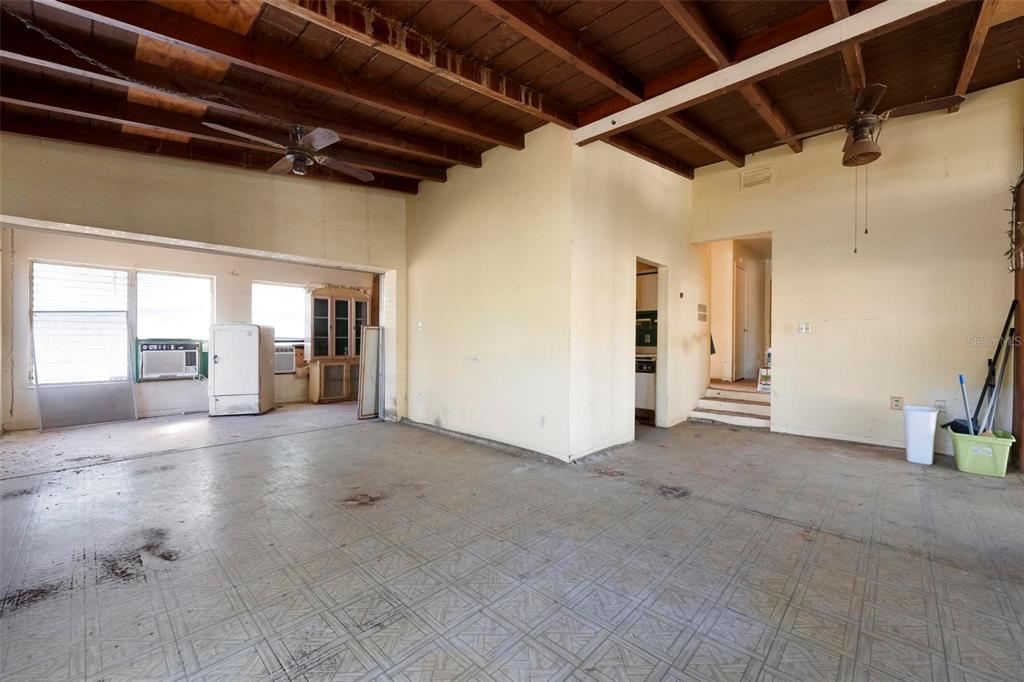 An open-concept living area features exposed wood ceiling beams, tile flooring, and a step-up hallway — 2956 GREENBRIAR STREET, SARASOTA, FL