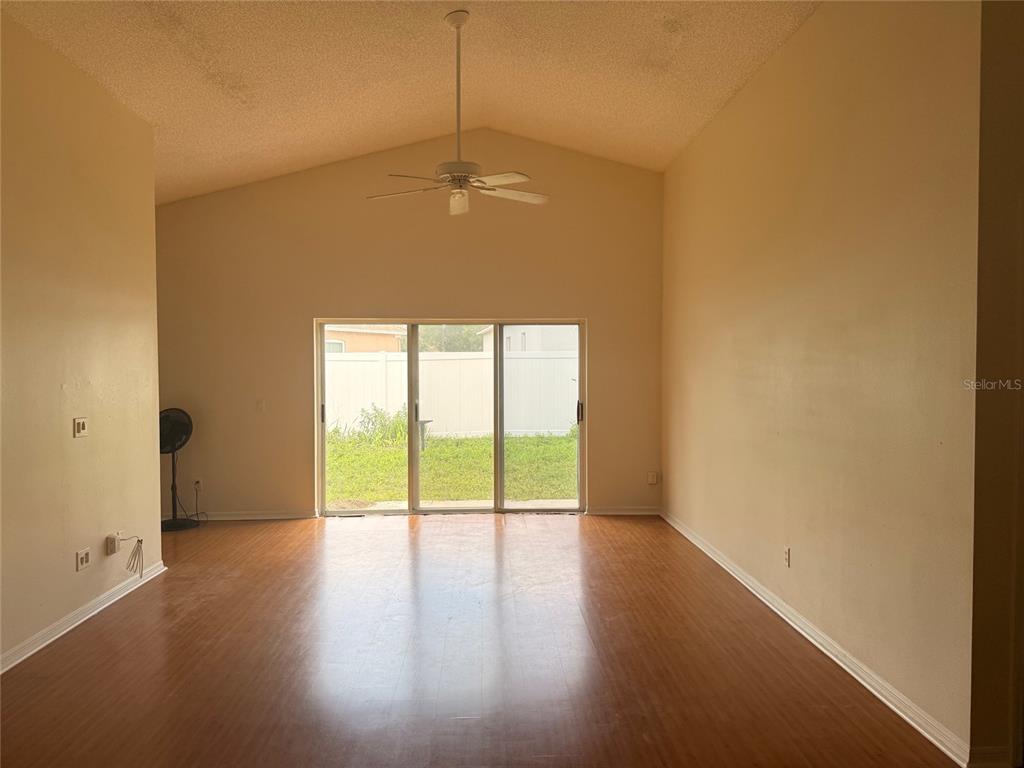 An empty living room with vaulted ceilings, a ceiling fan, and sliding glass patio doors — 610 TUTEN TRAIL, ORLANDO, FL
