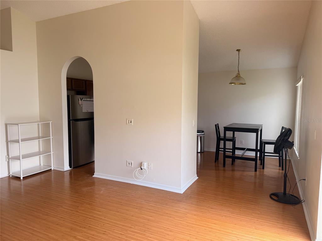A dining area and kitchen entrance with light wood flooring and beige walls — 610 TUTEN TRAIL, ORLANDO, FL