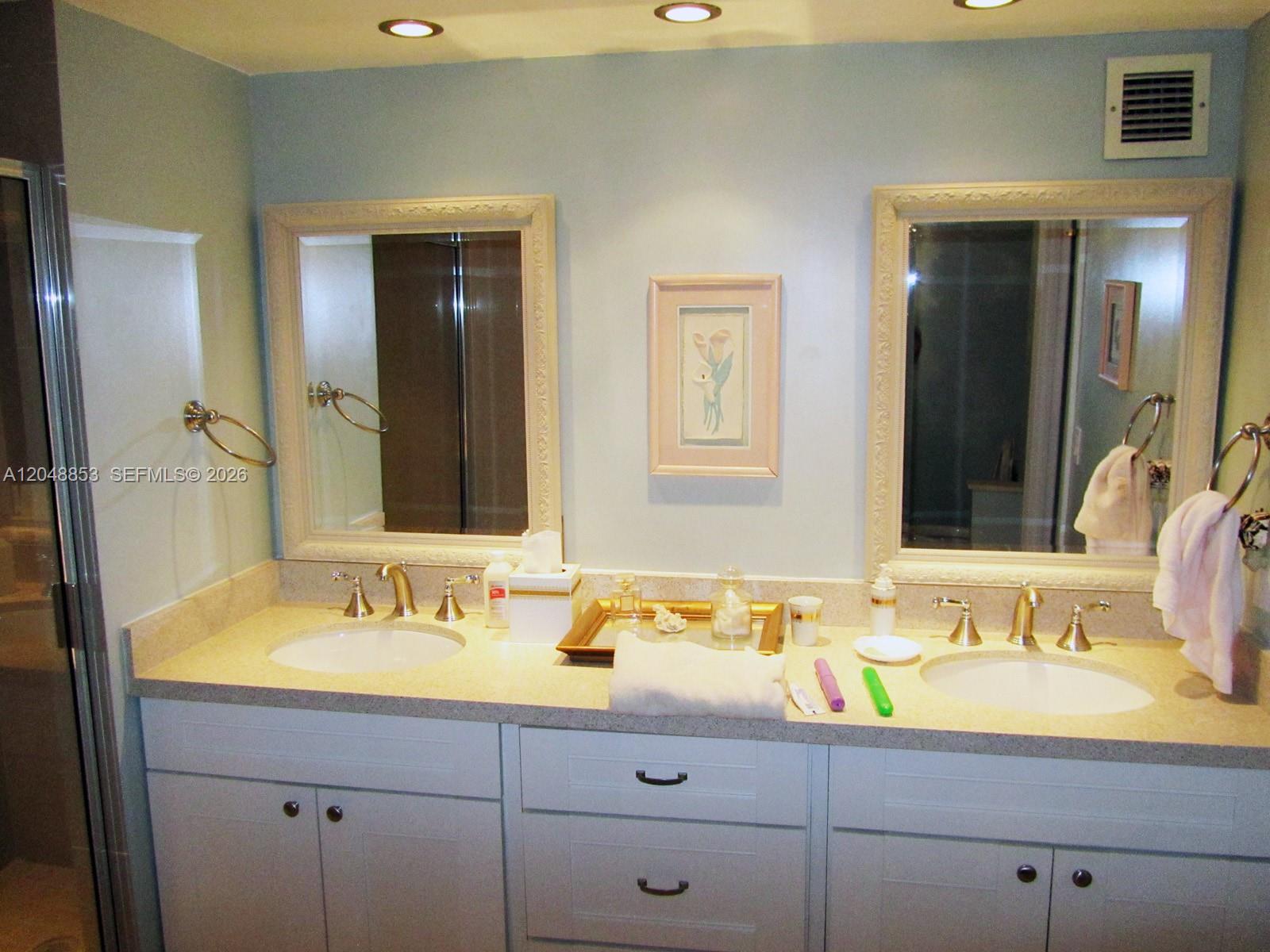 A bathroom features a double vanity with white cabinets, light countertops, and two framed mirrors — 1833 S Ocean Dr # 911, Hallandale Beach FL 33009, HALLANDALE BEACH, FL
