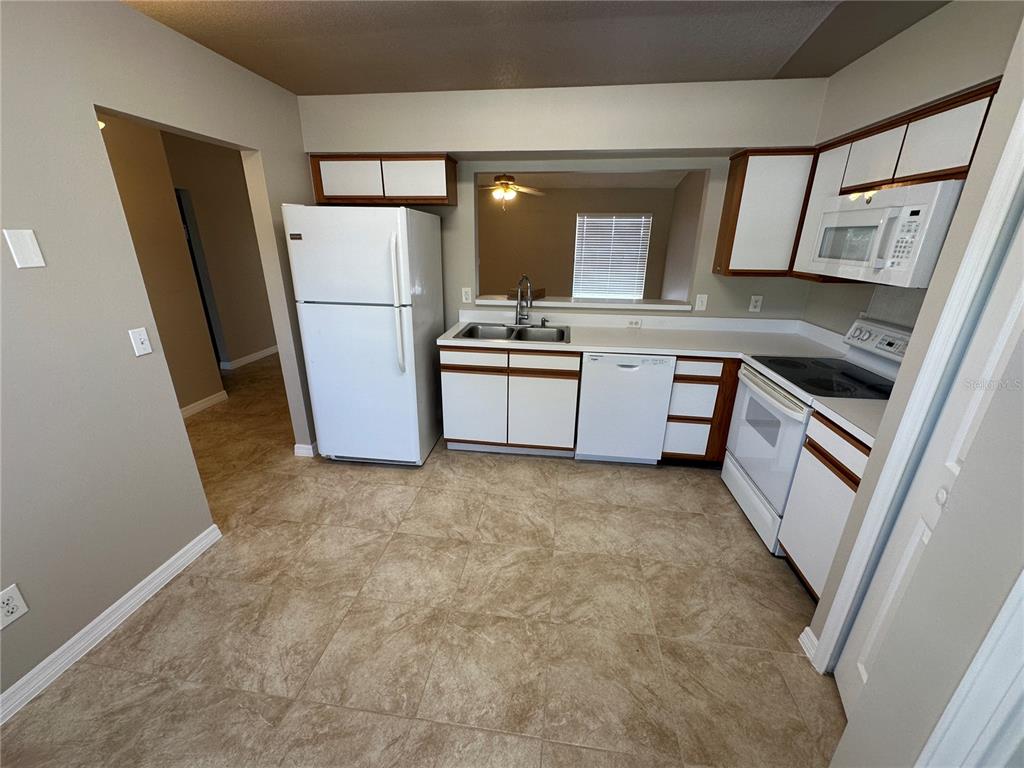 A kitchen features white appliances, wood-trimmed cabinets, and light-colored tile flooring — 660 MARLENE DRIVE, OCOEE, FL