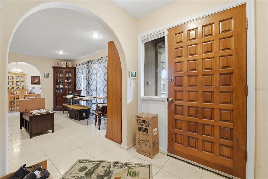 An entryway with a wooden paneled door, tiled floors, and an arched opening to another room — 701 MILAN COURT, ALTAMONTE SPRINGS, FL