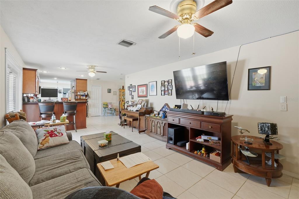 A living room with tile flooring, a ceiling fan, a television console, and an open kitchen — 701 MILAN COURT, ALTAMONTE SPRINGS, FL