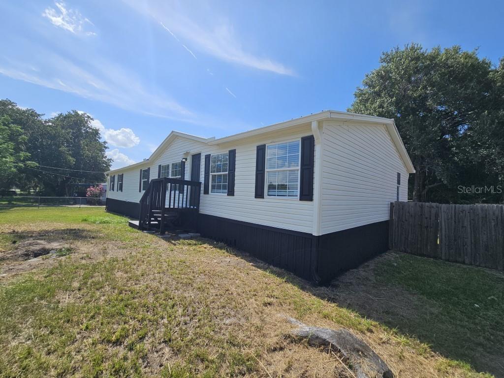 A single-story manufactured home with cream siding, black skirting, and a small wooden deck — 5105 COUNTRYSIDE COURT, ST CLOUD, FL