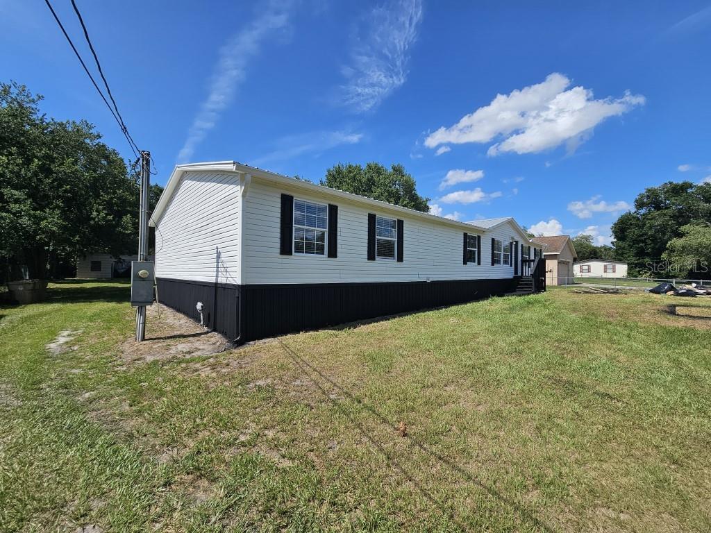 A side view of a white manufactured home with black skirting and a metal roof — 5105 COUNTRYSIDE COURT, ST CLOUD, FL