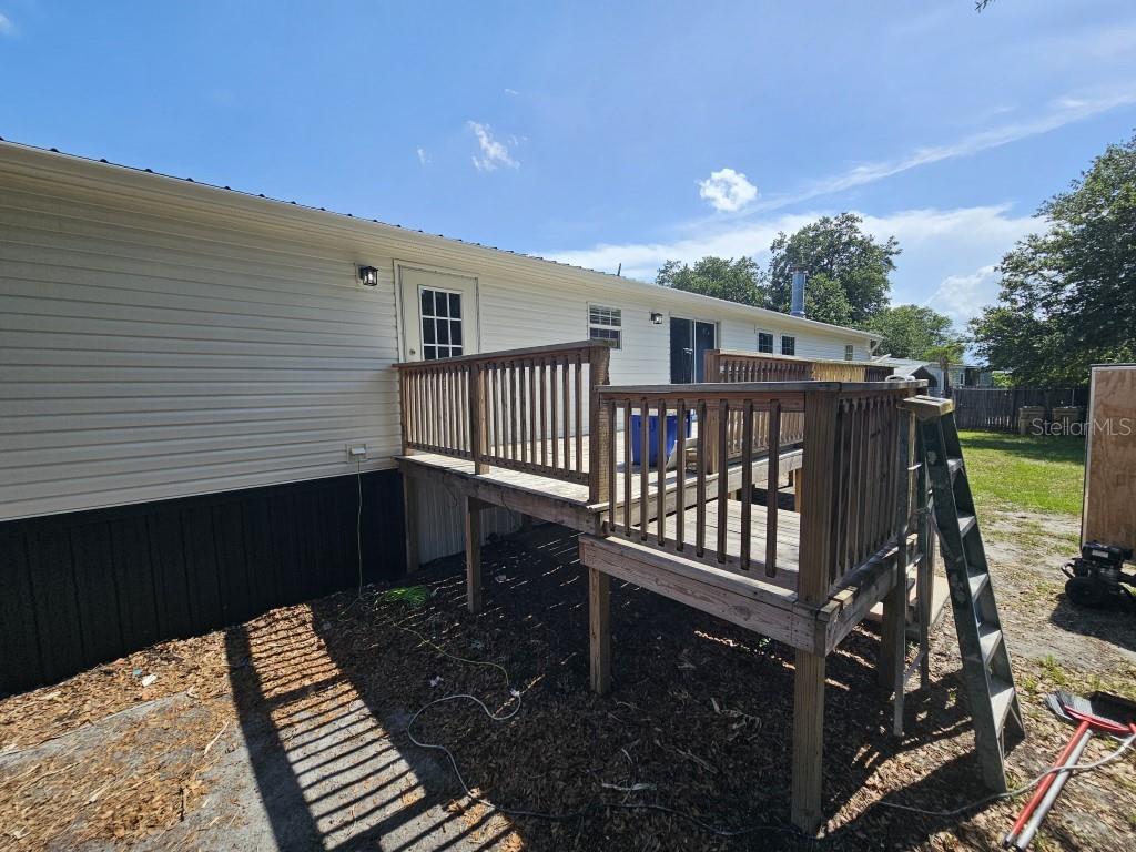 A wooden deck with railings is attached to the rear of a light-colored mobile home — 5105 COUNTRYSIDE COURT, ST CLOUD, FL