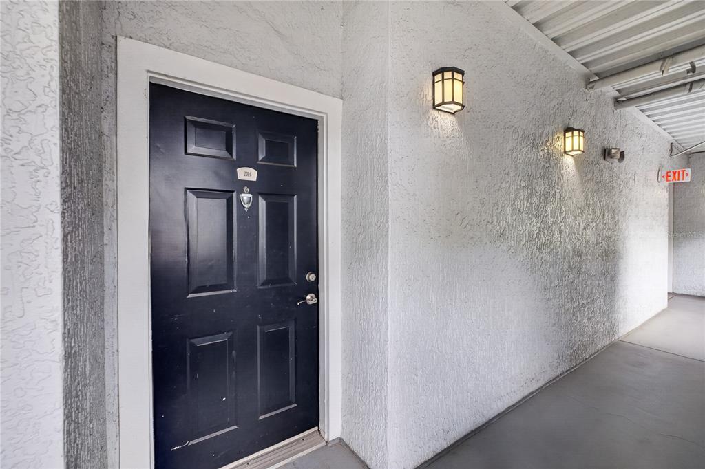 A dark blue front door with a peephole and number plate sits in a stucco hallway — 300 E SOUTH STREET UNIT 2014, ORLANDO, FL