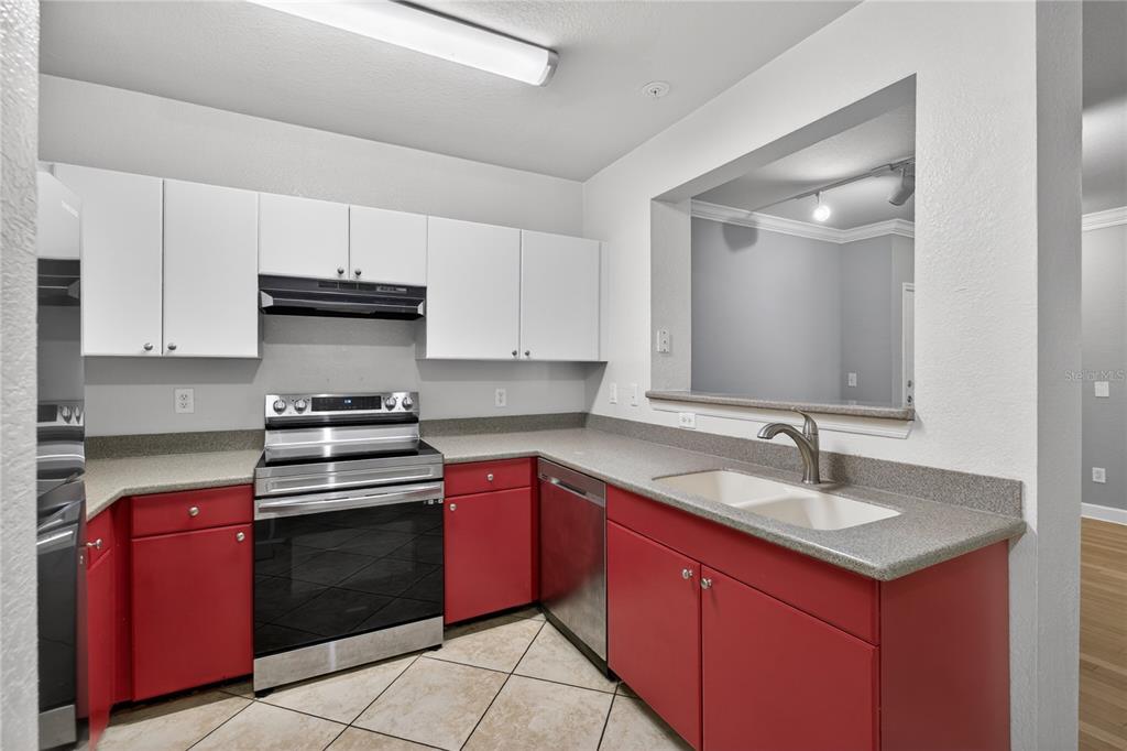 A kitchen features red lower cabinets, white upper cabinets, gray countertops, and tile flooring — 300 E SOUTH STREET UNIT 2014, ORLANDO, FL