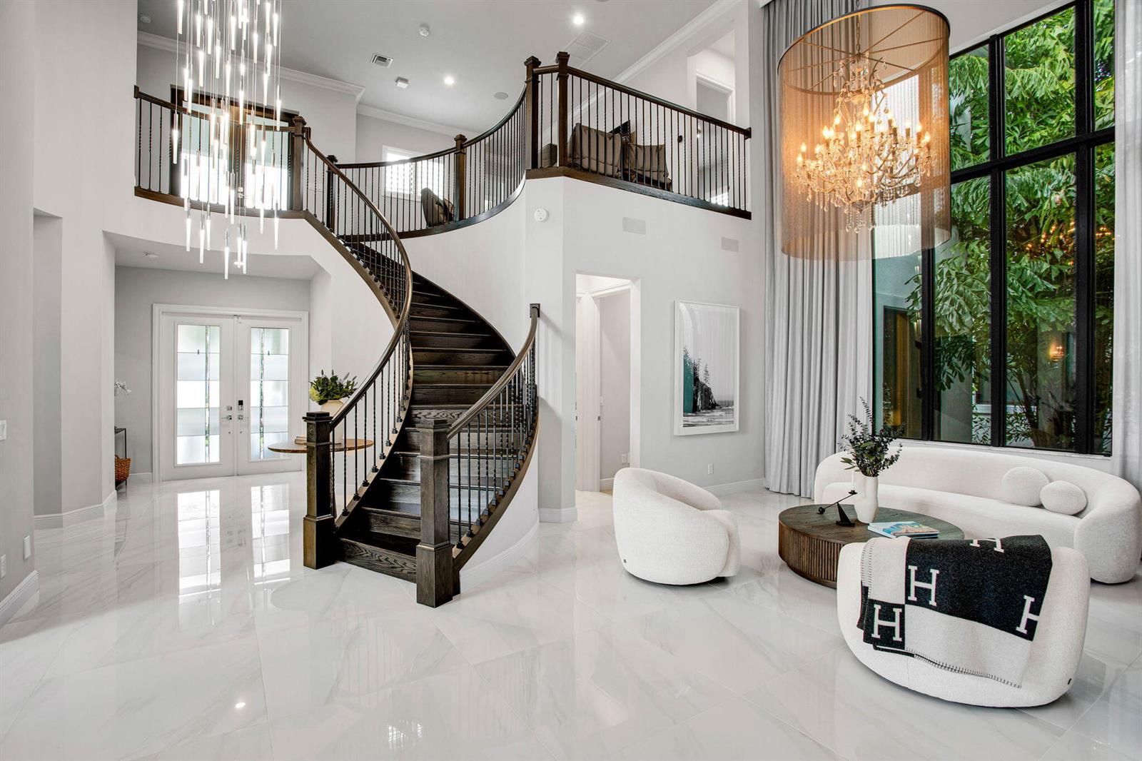 A grand foyer features a curved staircase, marble floors, and a large crystal chandelier — 6903 NW 28th Avenue, Boca Raton FL 33496, BOCA RATON, FL