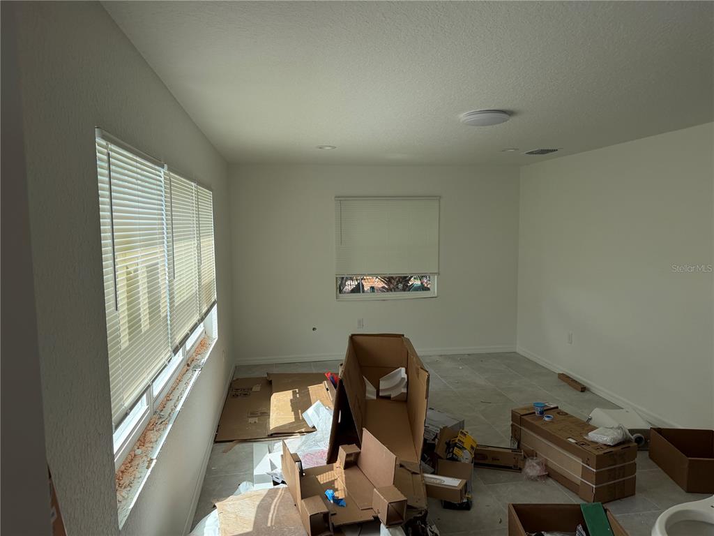 An unfurnished room with light tile flooring, white walls, and several windows with blinds — 6 S BARBOUR STREET, BEVERLY HILLS, FL