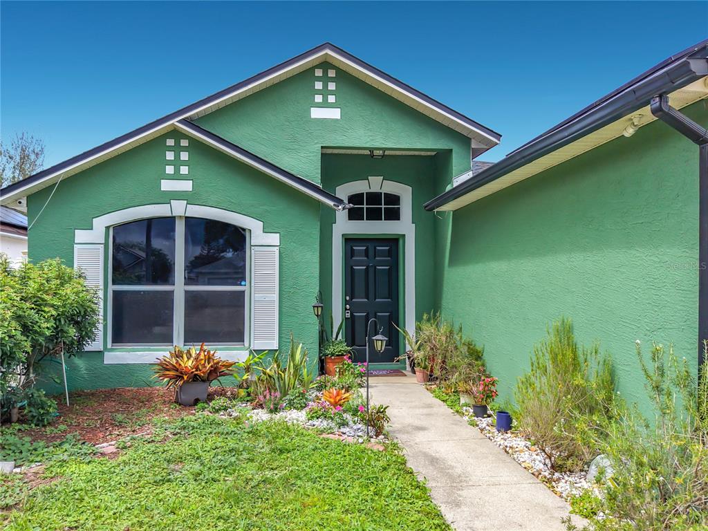 A green house exterior features a front door with a transom window and a walkway — 2131 CORNER SCHOOL DRIVE, ORLANDO, FL