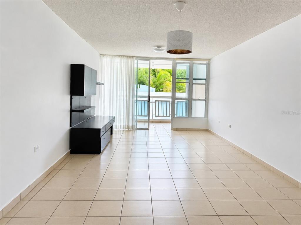 An empty living room features beige tile flooring, white walls, and a sliding glass door — CARR 844 1D-5 SAN JUAN CHALETS APT. 8050, SAN JUAN, PR