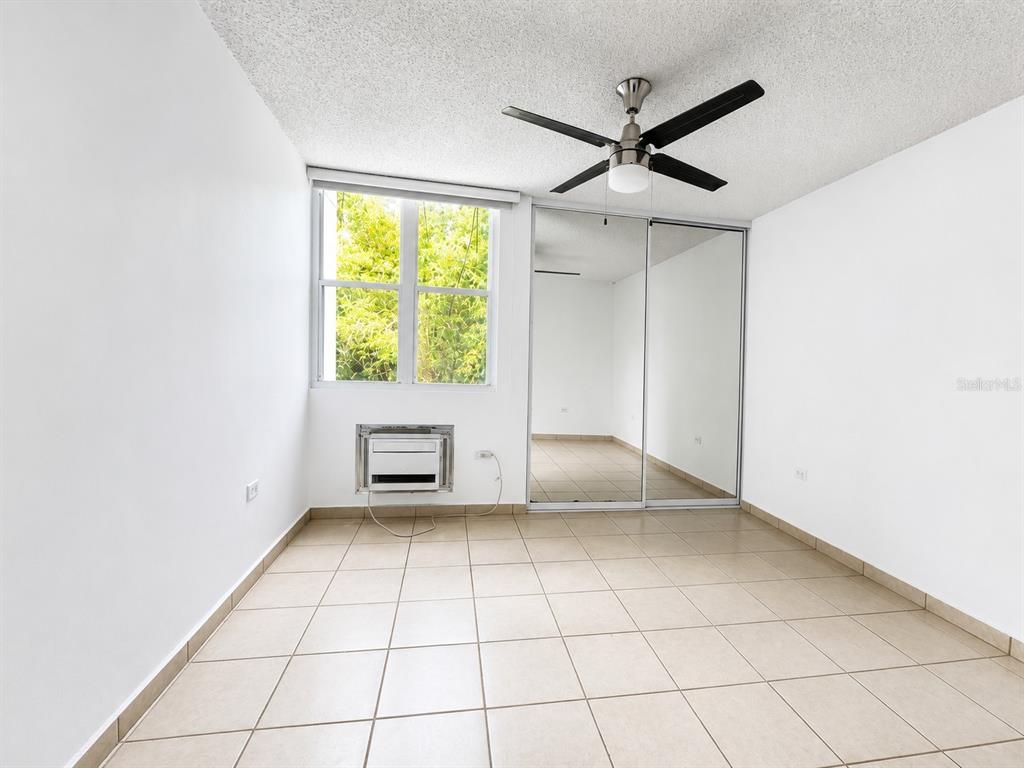 A bedroom with white walls, tile flooring, a ceiling fan, and mirrored closet doors — CARR 844 1D-5 SAN JUAN CHALETS APT. 8050, SAN JUAN, PR